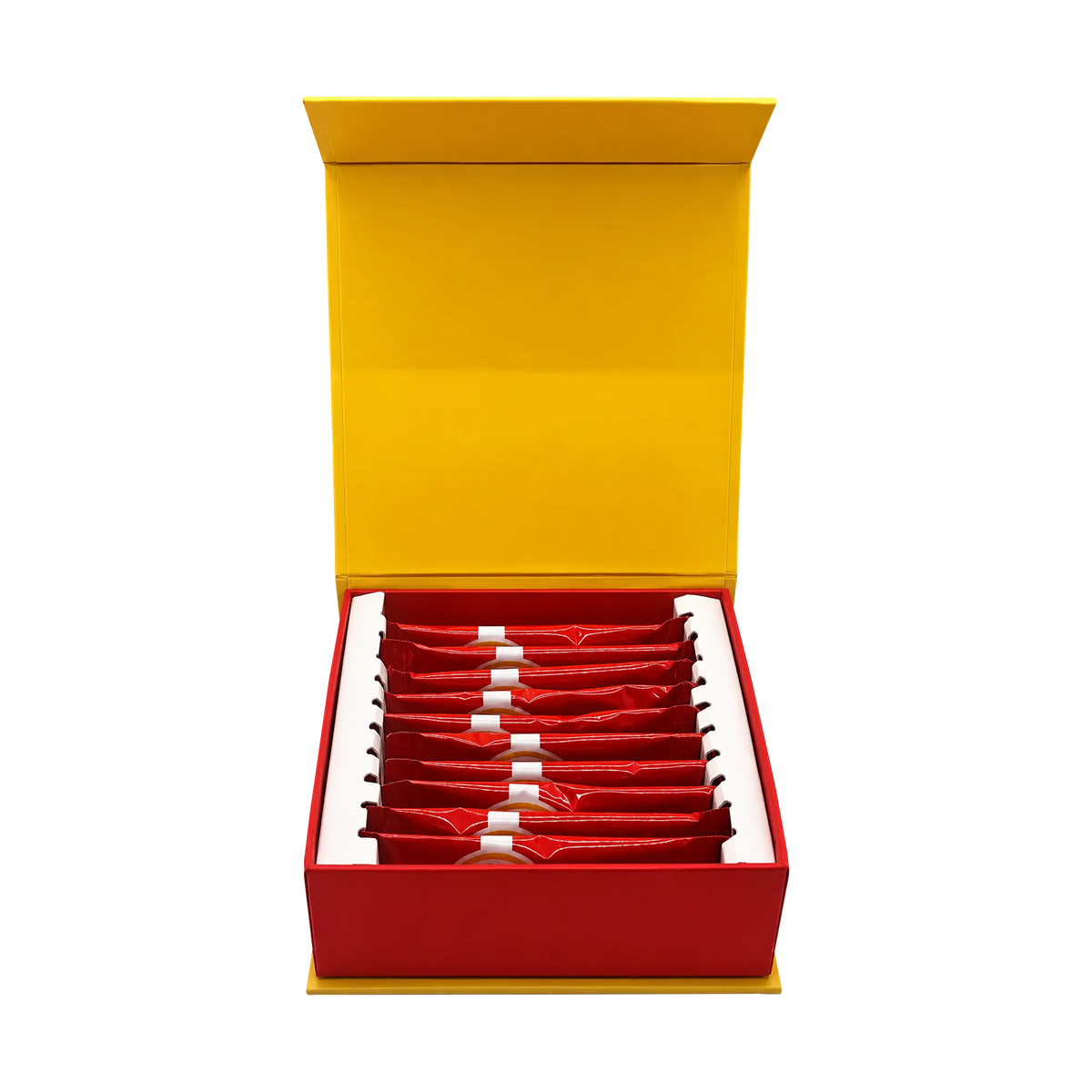 An open red gift box with a bright yellow interior lid, containing multiple small red sachets arranged in rows on a white insert, photographed on a plain white background.